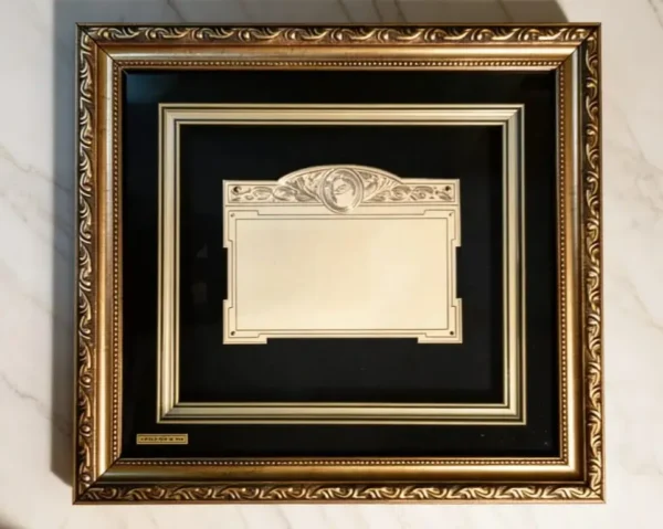 Plaqueta conmemorativa tipo cuadro con acabado en oro, marco decorativo y estuche de lujo de Nevey Medallas. Modelo 3500