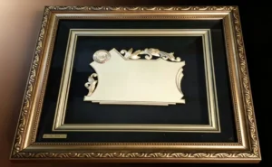 Plaqueta conmemorativa tipo cuadro con acabado en oro, marco decorativo y estuche de lujo de Nevey Medallas. Modelo 3600