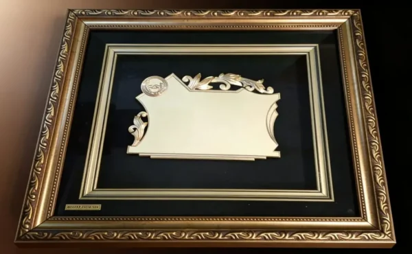 Plaqueta conmemorativa tipo cuadro con acabado en oro, marco decorativo y estuche de lujo de Nevey Medallas. Modelo 3600
