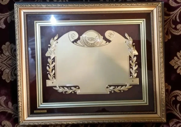 Plaqueta conmemorativa tipo cuadro con acabado en oro, marco decorativo y estuche de lujo de Nevey Medallas. Modelo 5600